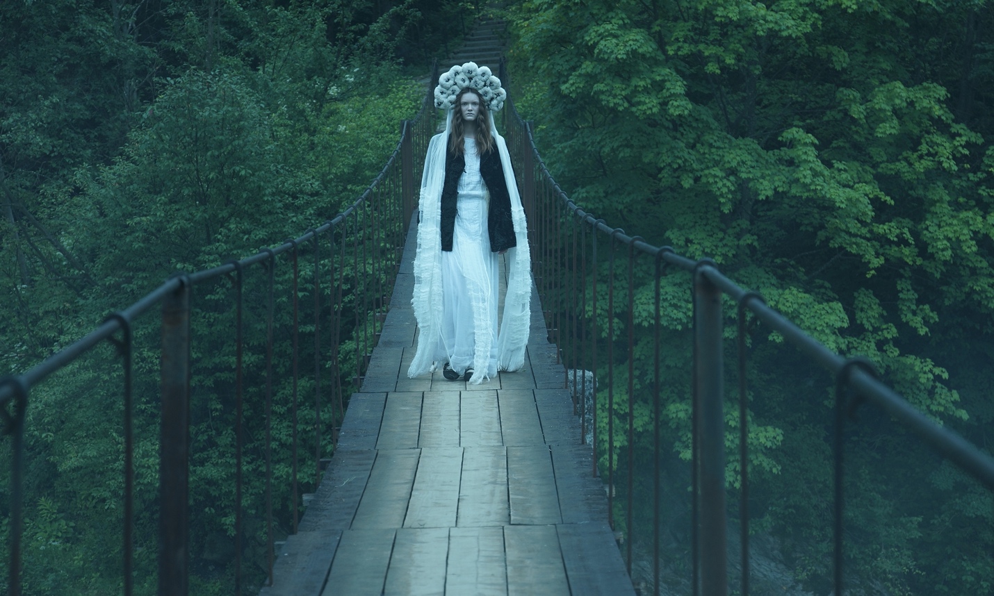 A person in a white dress and headdress on a bridge

Description automatically generated with low confidence