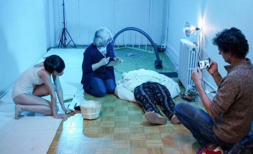 A group of people sitting on a bed Description automatically generated