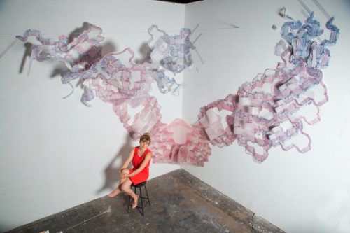 A picture containing a studio wall with frosted mylar drawing and the artists seated in front of it.