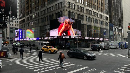 A street with cars and people on it with buildings in the back Description automatically generated with low confidence