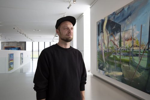 A person standing in front of a painting Description automatically generated with medium confidence