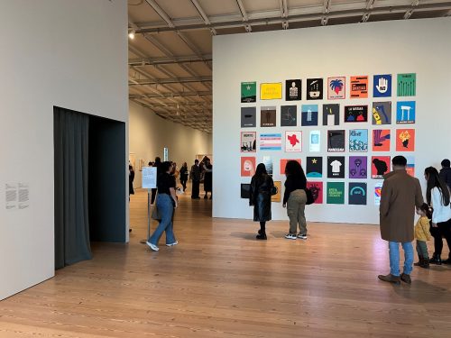 A group of people in a room with posters on the wall Description automatically generated with medium confidence