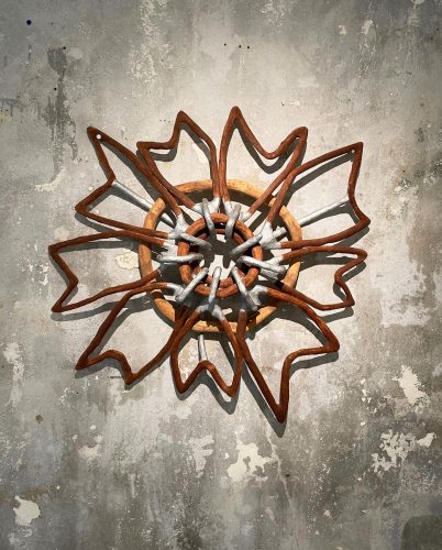 A metal flower on a wall Description automatically generated