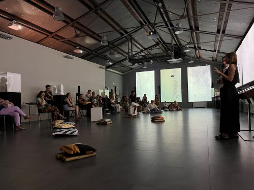 A person standing in a room with a group of people Description automatically generated