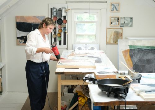 A person using a drill to drill a picture Description automatically generated