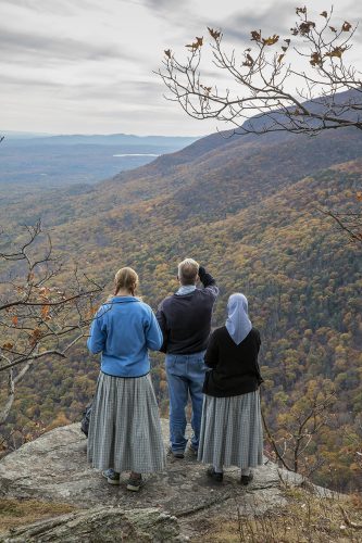 A group of people standing on a cliff overlooking a valley Description automatically generated