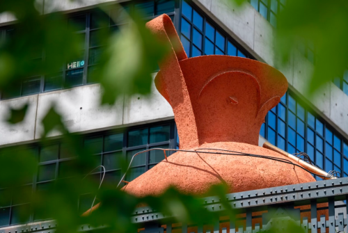 A large orange sculpture on top of a building Description automatically generated