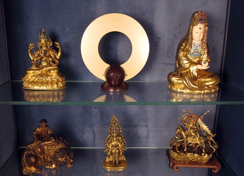 A collection of gold statues on a glass shelf Description automatically generated