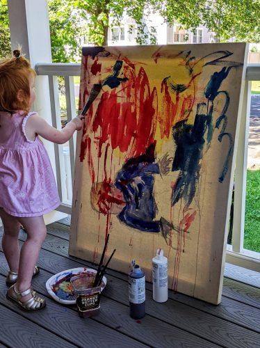 A child painting on a canvas Description automatically generated