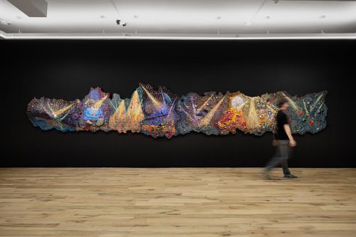 A person walking past a large art piece Description automatically generated