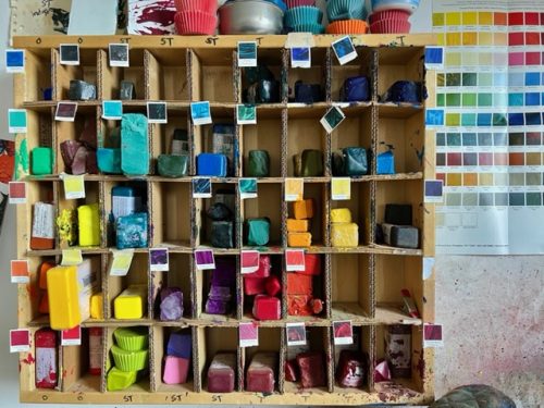 A shelf with different colors of paint Description automatically generated