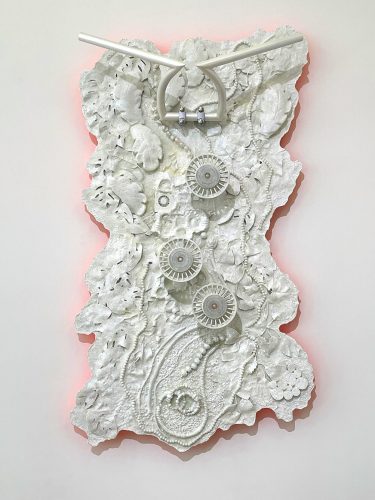 A white sculpture with gears and flowers Description automatically generated
