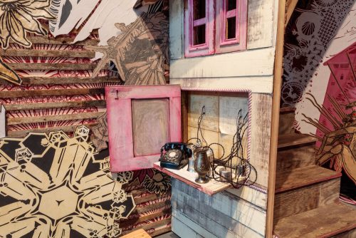 A room with a pink door and a shelf with a telephone and a wallpaper Description automatically generated with medium confidence