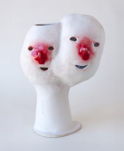 A white vase with red faces Description automatically generated