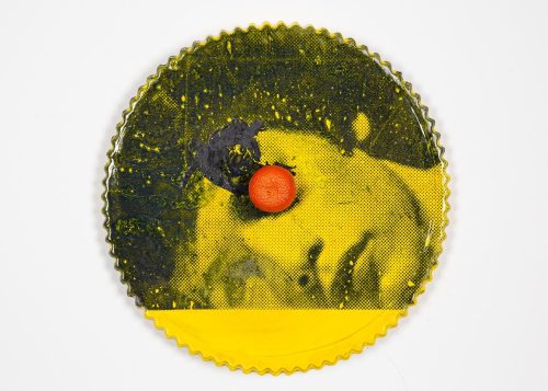 A round yellow and black object with a red dot on it Description automatically generated