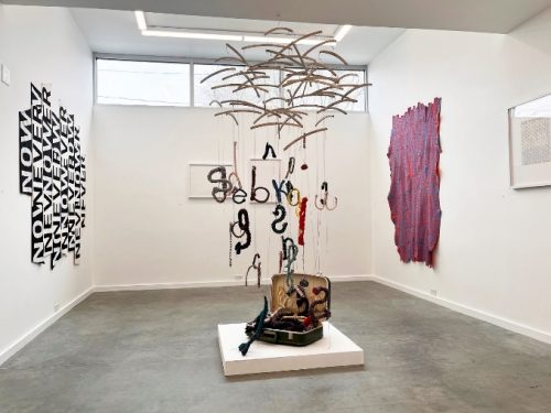 A room with a suitcase and objects from the ceiling Description automatically generated