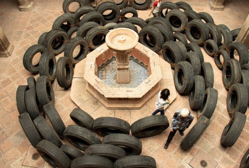 A group of people standing around a fountain with tires Description automatically generated