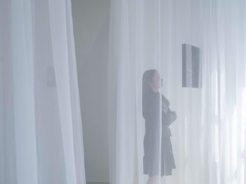 A person standing behind a curtain Description automatically generated