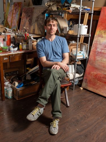 A person sitting in a chair in a studio Description automatically generated