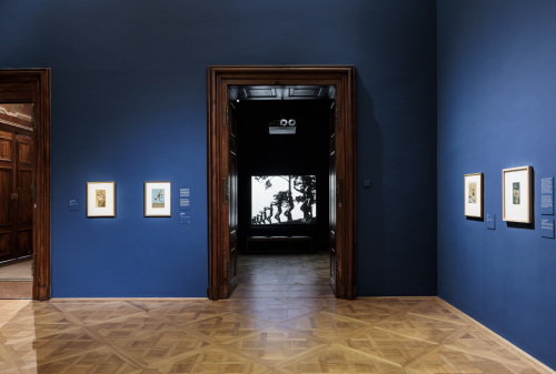 A room with a blue wall and a wooden door Description automatically generated