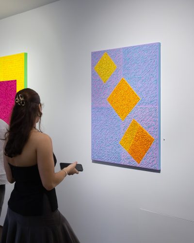 A person looking at a painting on a wall Description automatically generated