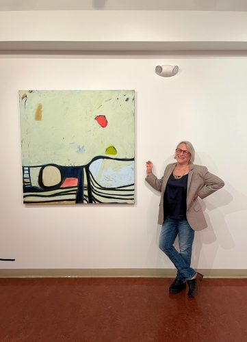 A person standing next to a painting Description automatically generated