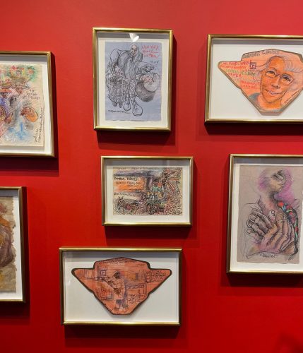 A group of framed pictures on a red wall Description automatically generated