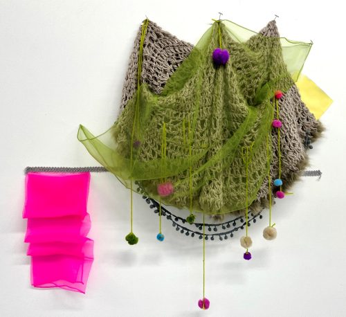 A green net with pompoms and a pink cloth on a white wall AI-generated content may be incorrect.