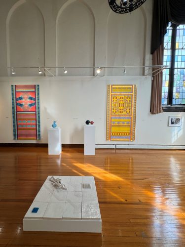 A room with a wood floor and a white table with art on it AI-generated content may be incorrect.