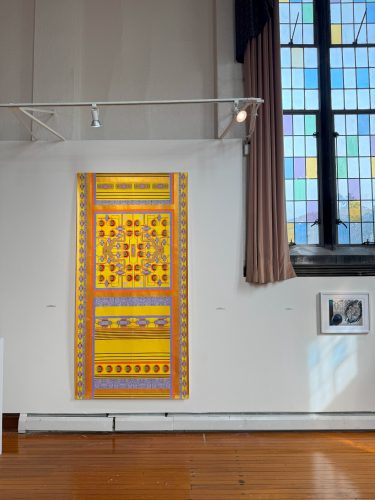 A yellow and orange art piece on a white wall AI-generated content may be incorrect.